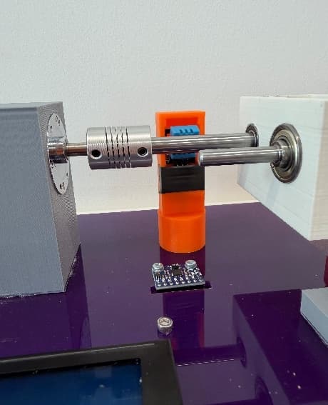 Close-up of the coupling, orange sensor housing and bearing on the rig.